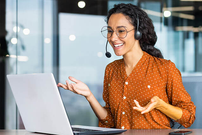 Young woman smiling while wearing headphones interacting with laptop