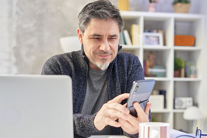 Older man at desk on mobile phone smiling