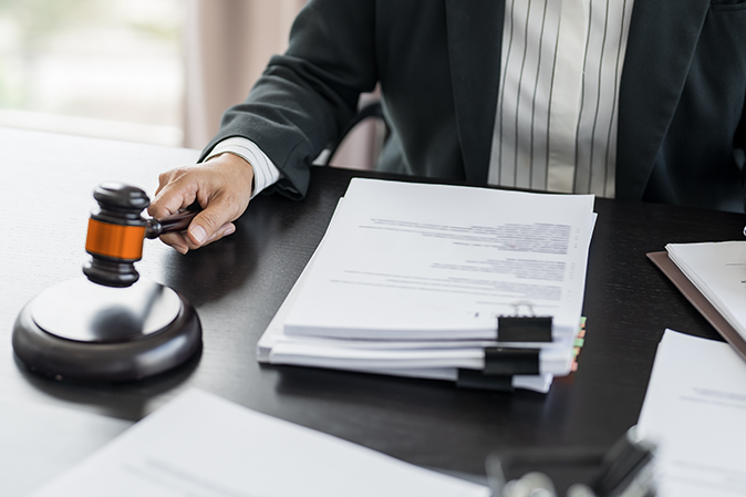 Man banging a gavel with pile of paperwork on his desk